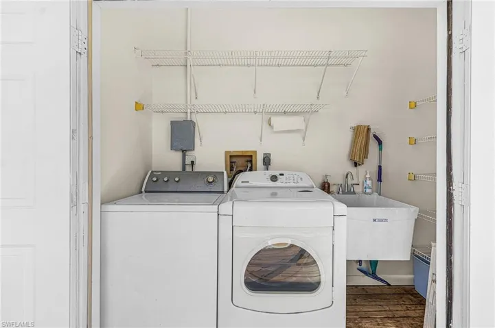 Upstairs laundry featuring washing machine, clothes dryer, soaking tub and storage.