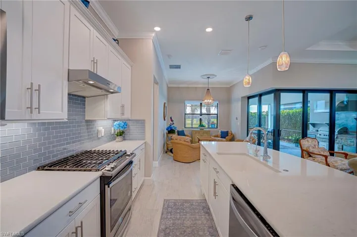 Kitchen featuring stainless steel appliances, white cabinetry, open floor plan, crown molding, and pendant lighting
