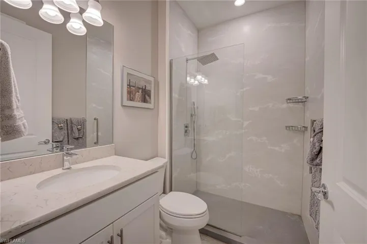 Bathroom with vanity, a marble finish shower, and recessed lighting