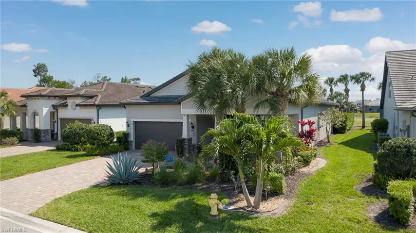 View of front of property featuring stucco siding, a front lawn, driveway, and a garage
