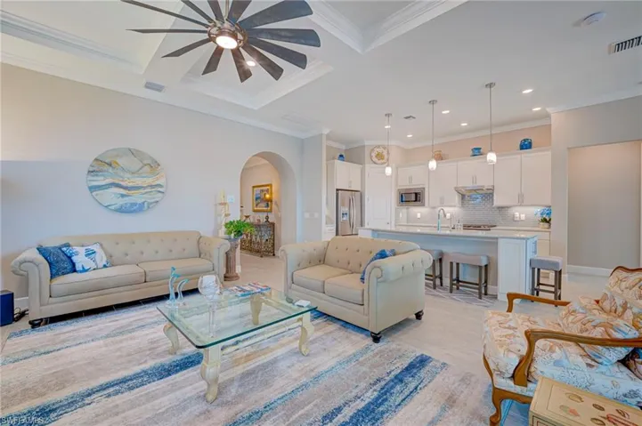 Living area featuring arched walkways, crown molding, ceiling fan, recessed lighting, and coffered ceiling