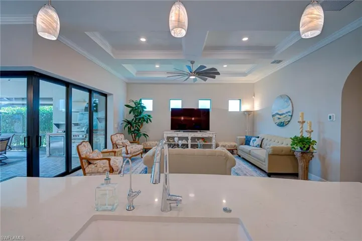 Living area featuring arched walkways, a ceiling fan, coffered ceiling, ornamental molding, and recessed lighting