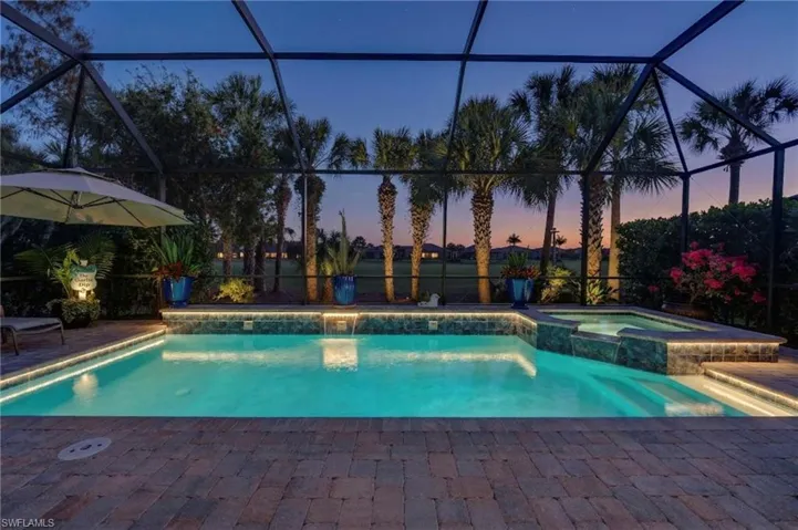 Pool at dusk with a pool with connected hot tub, a sunroom, a patio area