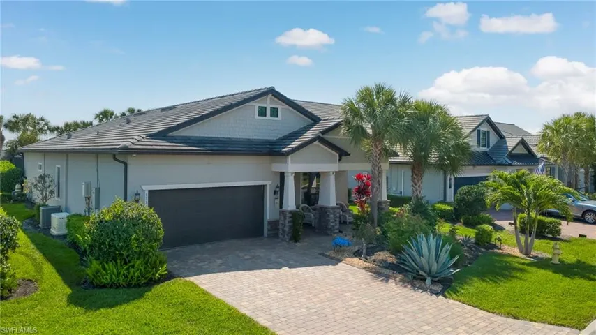 View of front facade with a garage, a front yard, decorative driveway, stucco siding, and stone siding