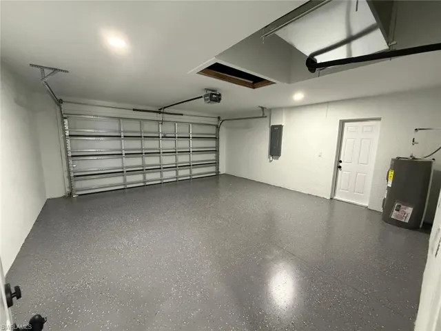 Garage with electric panel, a garage door opener, and water heater