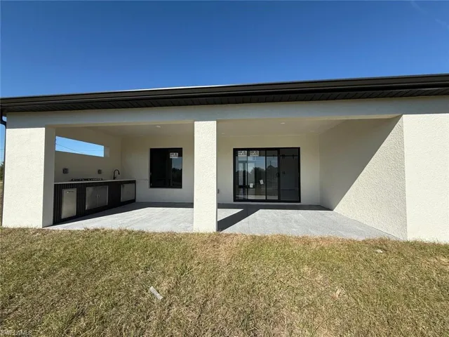 Back of property featuring stucco siding, a lawn, and a patio area