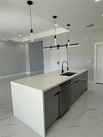 Kitchen with dishwasher, a barn door, marble finish floor, modern cabinets, and a sink