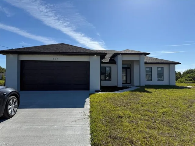 Prairie-style house featuring concrete driveway, a front yard, roof with shingles, stucco siding, and a garage