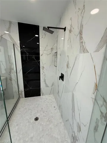 Bathroom featuring a marble finish shower and stone wall