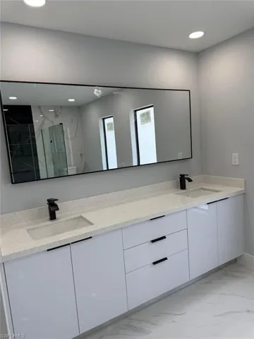 Bathroom featuring a sink, marble finish floor, and double vanity