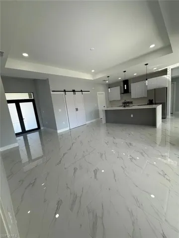 Unfurnished living room with recessed lighting, baseboards, and a raised ceiling