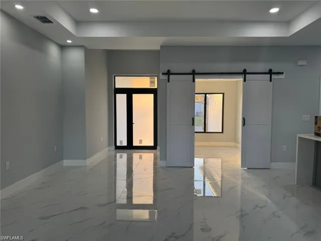 Unfurnished room with recessed lighting, baseboards, and a barn door