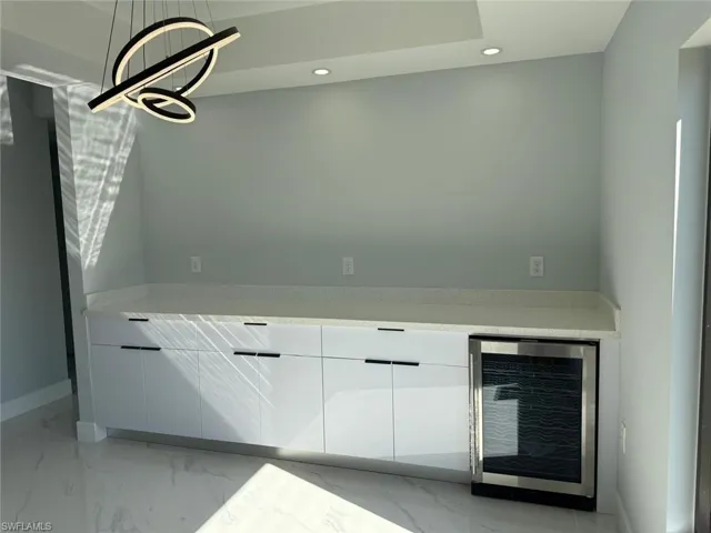 Kitchen featuring recessed lighting, wine cooler, white cabinets, modern cabinets, and marble finish floor