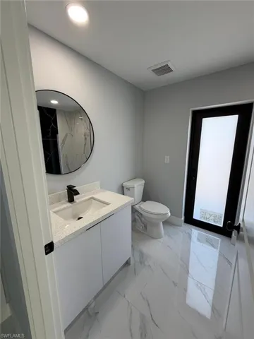 Full bathroom featuring vanity, visible vents, recessed lighting, toilet, and marble finish floor