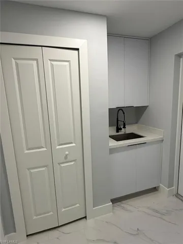 Bar with a sink, baseboards, and marble finish floor