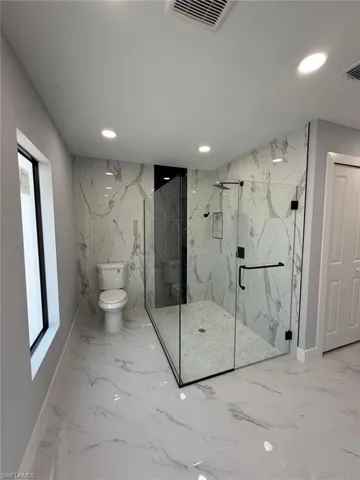 Bathroom featuring recessed lighting, visible vents, marble finish floor, and stone wall