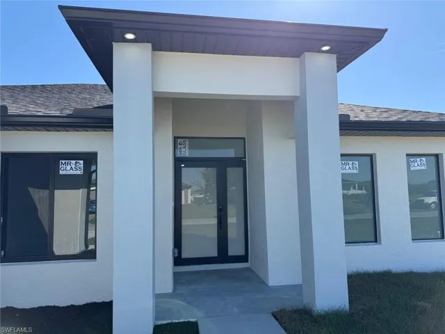 Property entrance with stucco siding and roof with shingles