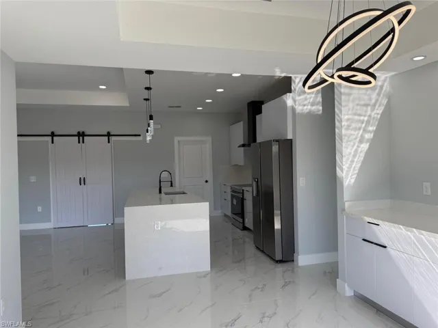 Kitchen featuring stainless steel electric stove, a barn door, refrigerator with ice dispenser, modern cabinets, and marble finish floor