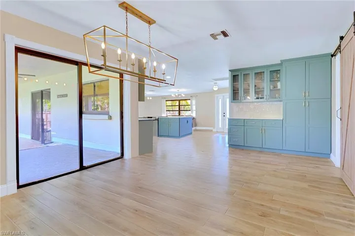 Unfurnished dining area featuring a barn door, light wood-type flooring, and a chandelier