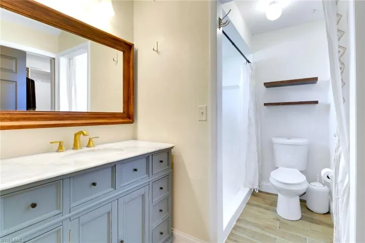 Full bath with vanity, light wood-style floors, and a shower stall