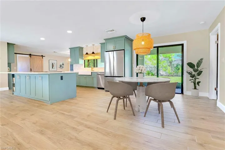 Kitchen featuring green cabinetry, a barn door, stainless steel appliances, a kitchen island, and recessed lighting