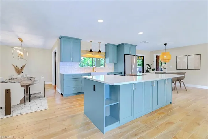 Kitchen with hanging light fixtures, blue cabinetry, a center island, freestanding refrigerator, and recessed lighting