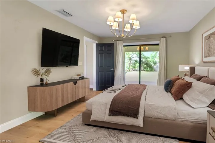 Bedroom featuring light wood finished floors, access to exterior, and a chandelier