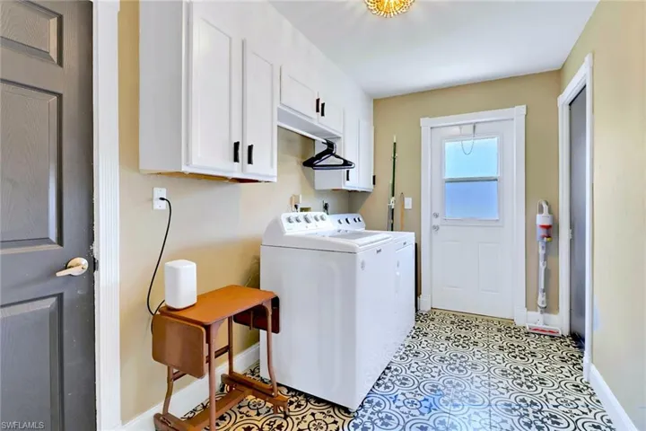 Laundry room featuring cabinet space, washer and dryer, and light tile patterned floors