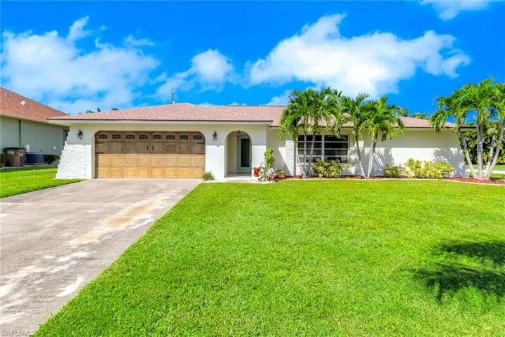 Single story home featuring driveway, stucco siding, an attached garage, and a front lawn