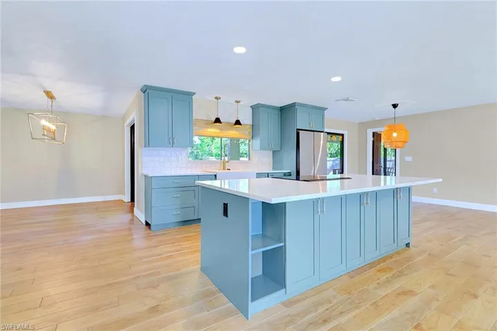 Kitchen featuring pendant lighting, a center island, freestanding refrigerator, recessed lighting, and light wood-type flooring