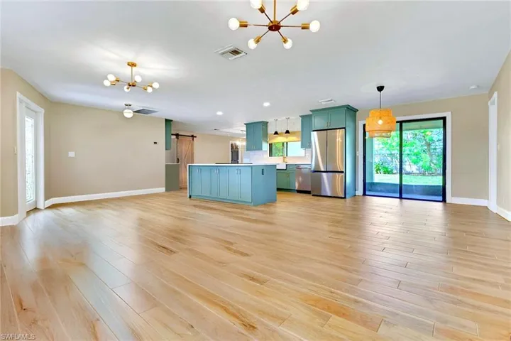 Kitchen featuring open floor plan, a chandelier, a barn door, and green cabinetry