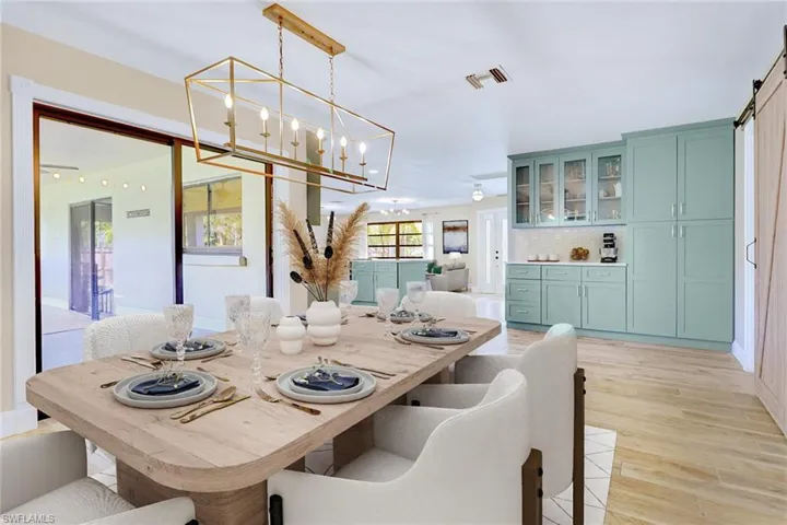Dining area featuring a barn door, light wood-style floors, and a chandelier