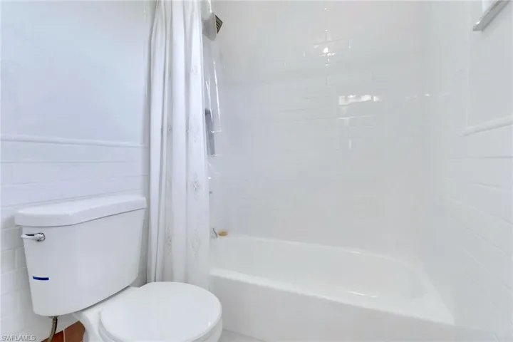 Full bathroom featuring shower / bathtub combination with curtain and toilet