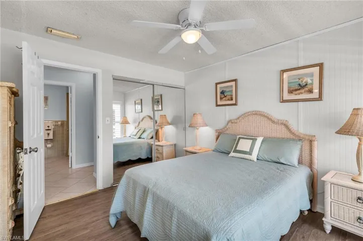Bedroom featuring a textured ceiling, a closet, ceiling fan, and wood finished floors