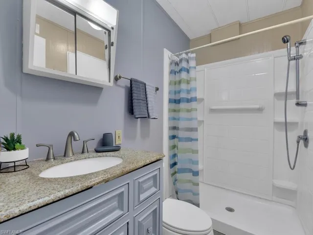 Bathroom featuring walk in shower, large vanity, and toilet