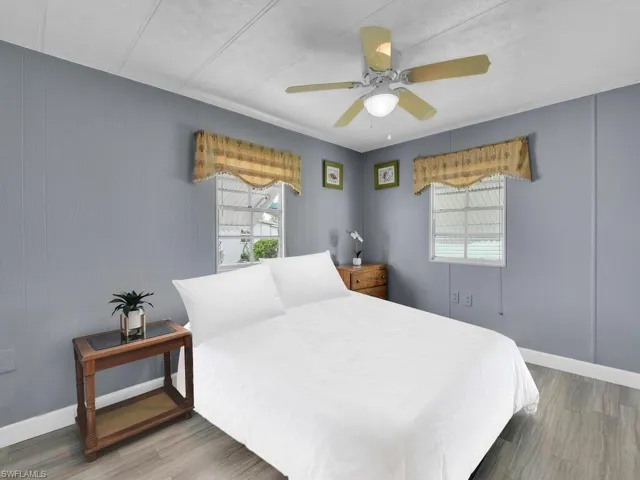 Bedroom featuring ceiling fan, multiple windows, and hardwood / wood-style floors