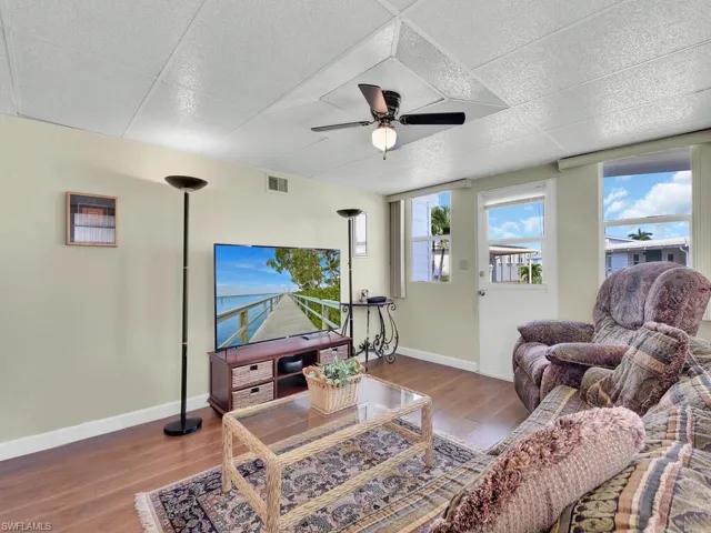 Living room with hardwood / wood-style flooring, a paneled ceiling, and ceiling fan
