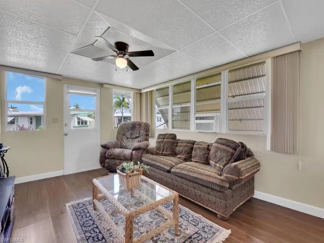 Living room with dark hardwood / wood-style floors, ceiling fan, and a paneled ceiling