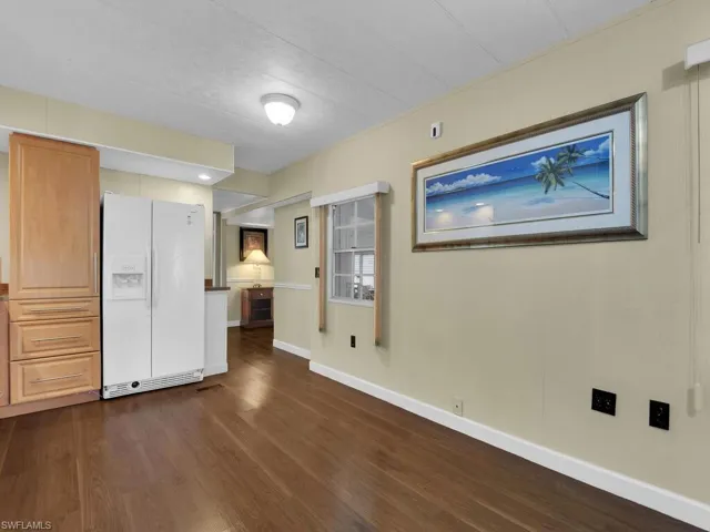 Unfurnished bedroom with white fridge with ice dispenser and dark wood-type flooring