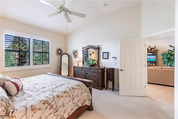 Bedroom featuring vaulted ceiling, light colored carpet, and ceiling fan