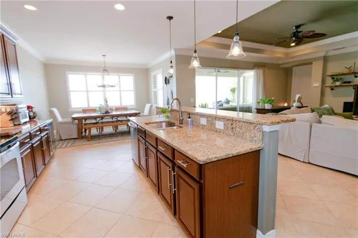 Kitchen featuring hanging light fixtures, crown molding, light tile patterned floors, recessed lighting, and light stone countertops