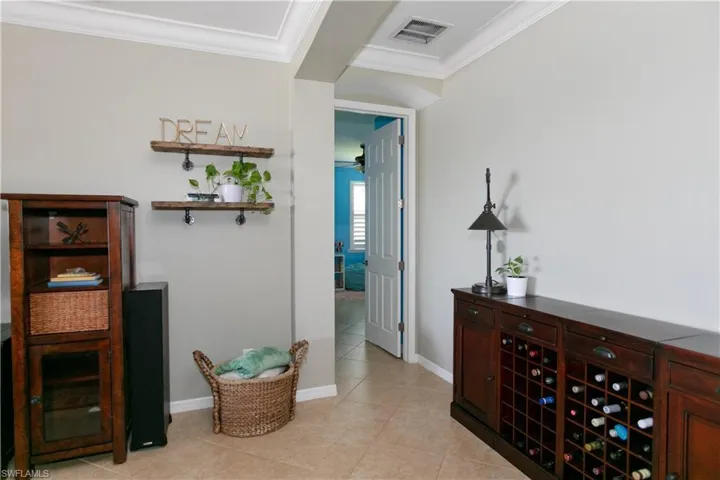 Hallway featuring crown molding, light tile patterned floors, baseboards, and visible vents