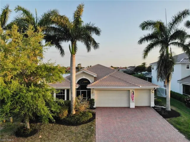 View of front of property featuring an attached garage, a tiled roof, stucco siding, and decorative driveway
