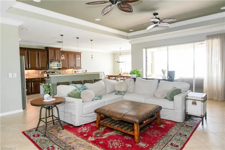 Living area featuring light tile patterned floors, crown molding, a ceiling fan, a tray ceiling, and recessed lighting