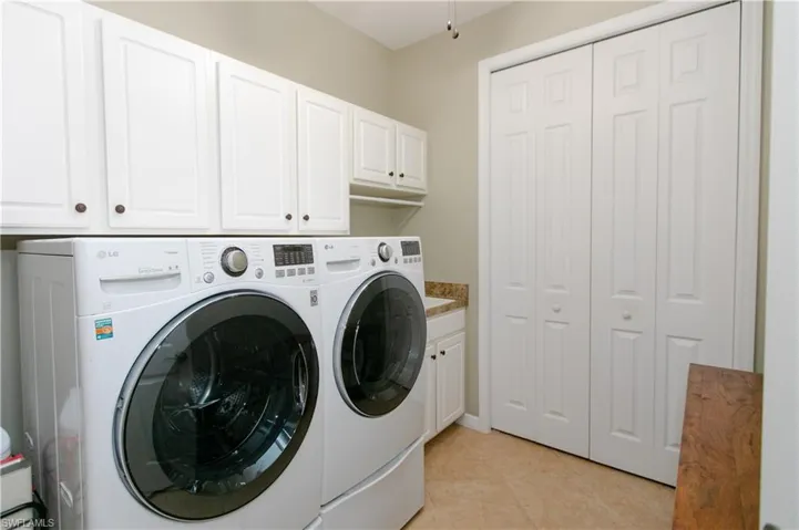 Clothes washing area featuring washer and dryer, tile floors and  large closet