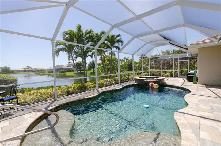 View of pool featuring a water view, a patio area, a pool with connected hot tub.