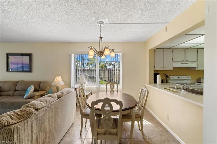 Dining area with light tile patterned floors, a chandelier, and a textured ceiling