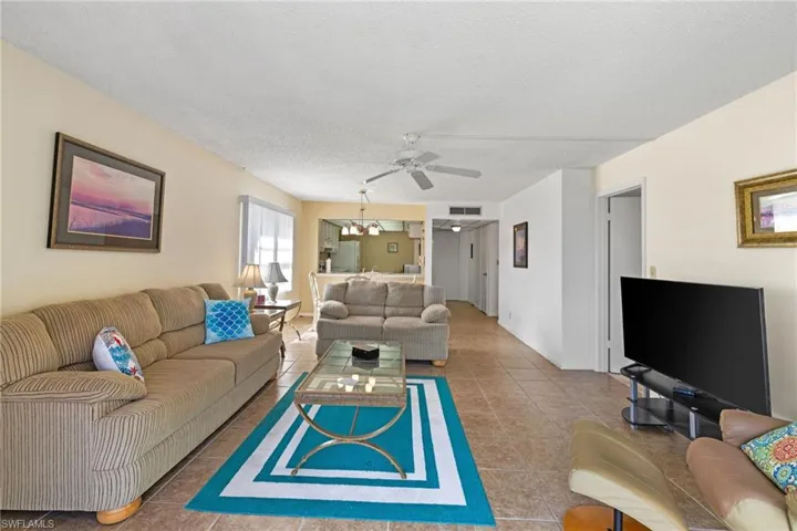 Living room with a textured ceiling, tile patterned flooring, and a ceiling fan