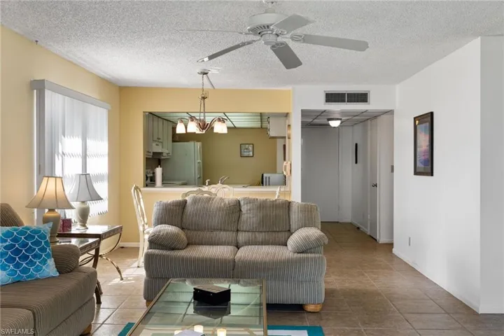Living room with a textured ceiling, ceiling fan, and tile patterned floors