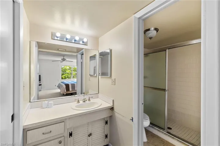 Bathroom featuring connected bathroom, vanity, a stall shower, light tile patterned flooring, and ceiling fan